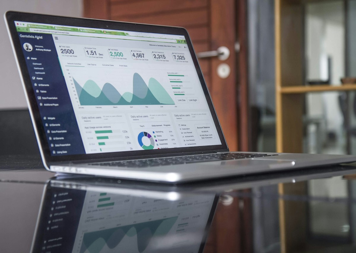 Laptop displaying analytical information beside business reports
